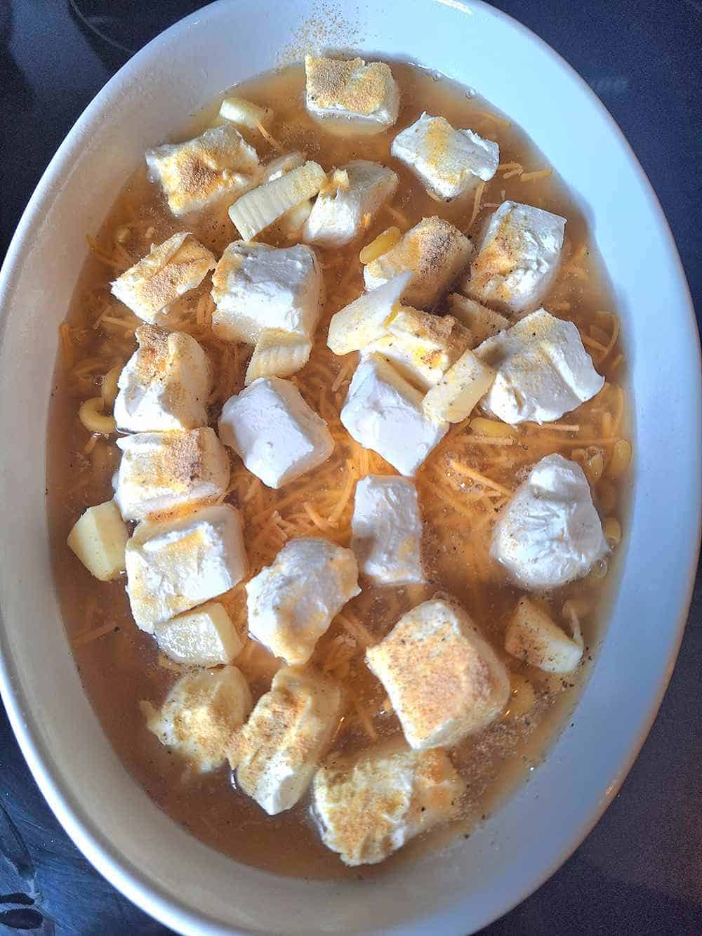 The low sodium macaroni and cheese ingredients in a baking dish prior to being stirred.