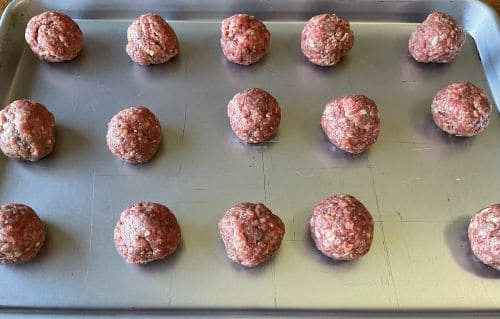 Rolled raw meatballs on baking sheet