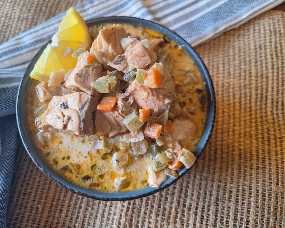 The finished Simple Salmon Stew Recipe in a bowl with a wedge of lemon
