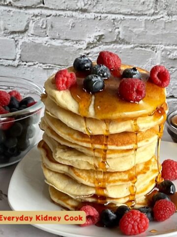 Tall stack of low sodium pancakes with berries and syrup